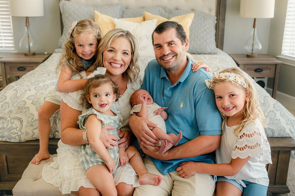A Houston TX family of 6 smiles during an in-home newborn photoshoot with Cypress Newborn Photographer 