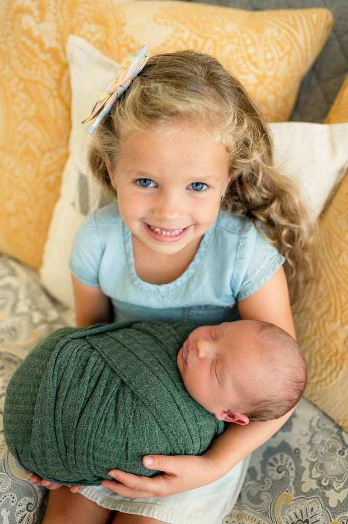 A proud big sister holds her newborn baby brother during colorful family photos with Houston newborn photographer, Mel B Photo 