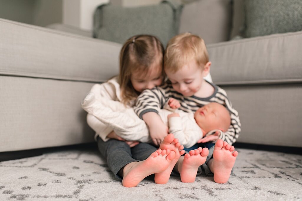 A Texas newborn is shown with his two older siblings during a lifestyle newborn and family session that took place in their Northern Houston area home with Mel B Photo.