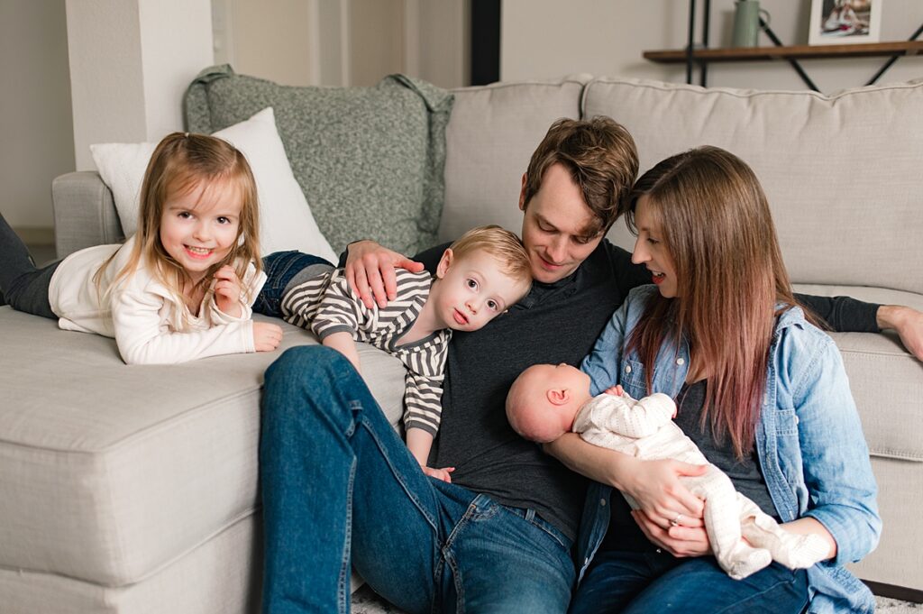 A family of 5 is pictured in their neutral living room during a Houston area in-home newborn session with Texas newborn and family photographer, Mel B Photo