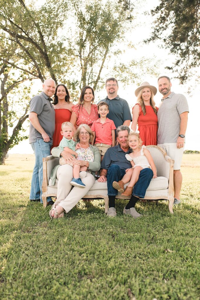 Multiple generations of a Texas family are photographed standing around a cream colored sofa on the lawn of their home during a lifestyle family session with Mel B Photo.