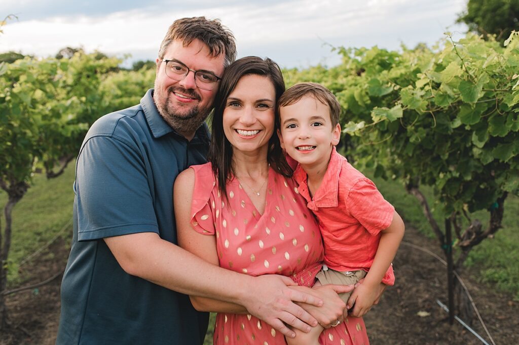 A Texas family of 3 is photographed in a vineyard by Cypress Family Photographer, Mel B Photo. 