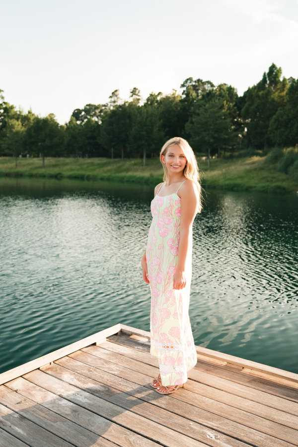 A young woman poses next to a local lake during an outdoor photoshoot with a family photographer cypress tx.
