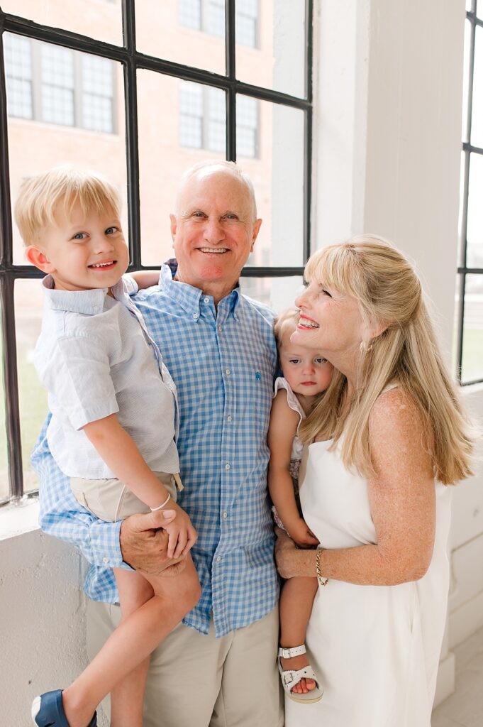 Two adults hold two young children during a Houston family photoshoot in a natural light studio 