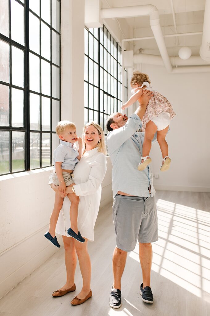 A father lifts his daughter into the air and smiles during a family photoshoot with Woodlands family photographer, Mel B Photo 