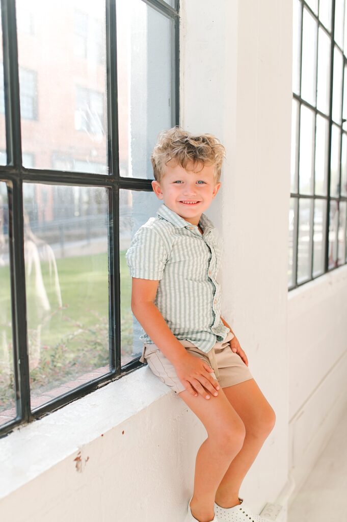 A Houston toddler is photographed seated in the window of a natural light studio during a Houston family photo shoot with Mel B Photo 