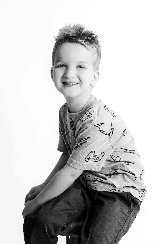 A black and white solo portrait of a young boy smiling at a portrait studio houston tx