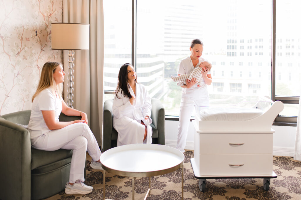 The Ruby Postnatal staff holds a newborn baby as a new mother looks on from her chair in her luxury suite 