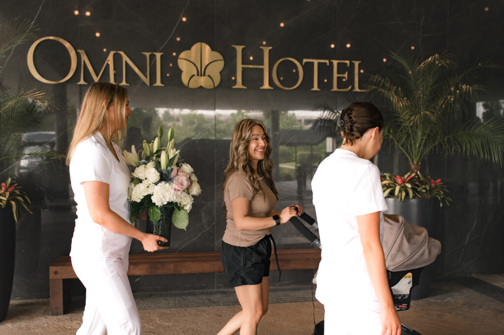 The Omni Hotel signage is pictured as a new mother and her baby make their way to the Ruby Postnatal suite with support staff 