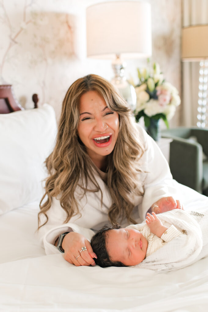A new mom smiles with her swaddled newborn in a session with Houston newborn photographer Mel B Photo at The Ruby Postnatal