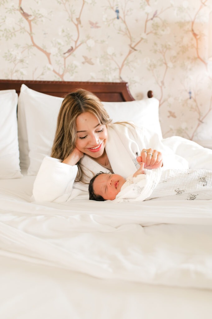 A new mom admires her swaddled newborn in a session with Houston newborn photographer Mel B Photo at The Ruby