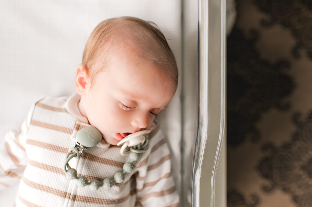 A Houston TX newborn is photographed by Mel B Photo in a striped sleeper and paci in The Ruby Postnatal 