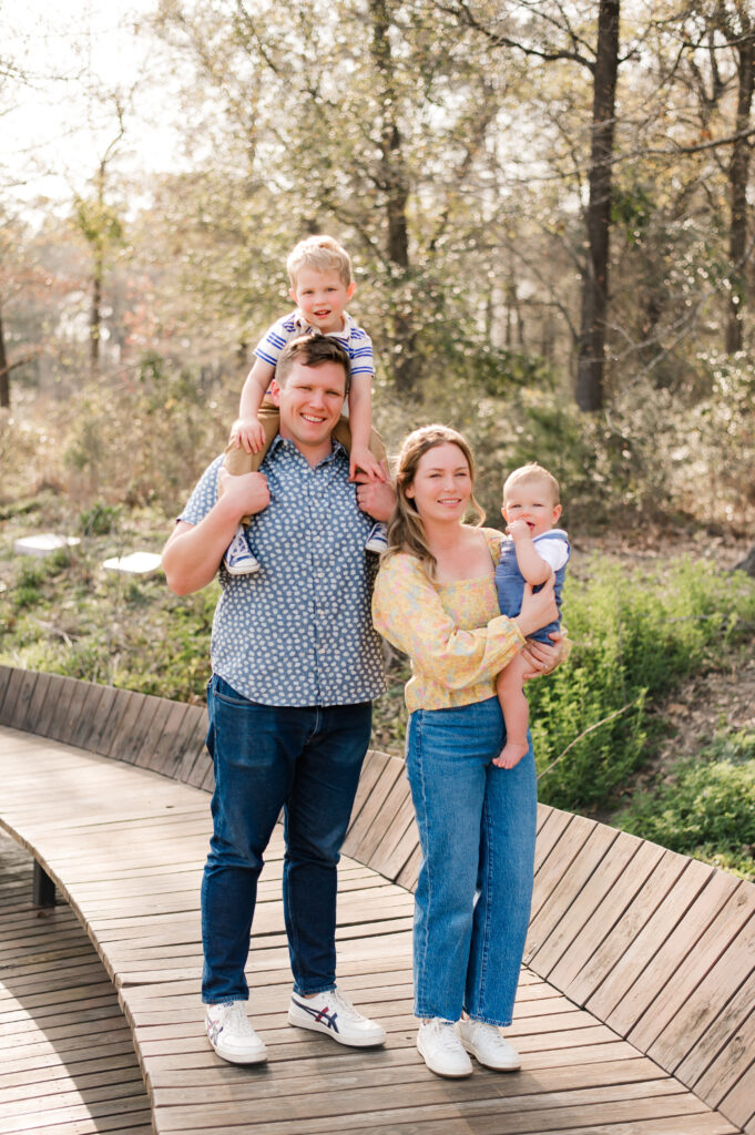 A Texas family of four smiles for a photo taken at Memorial Park during family photography in Houston TX