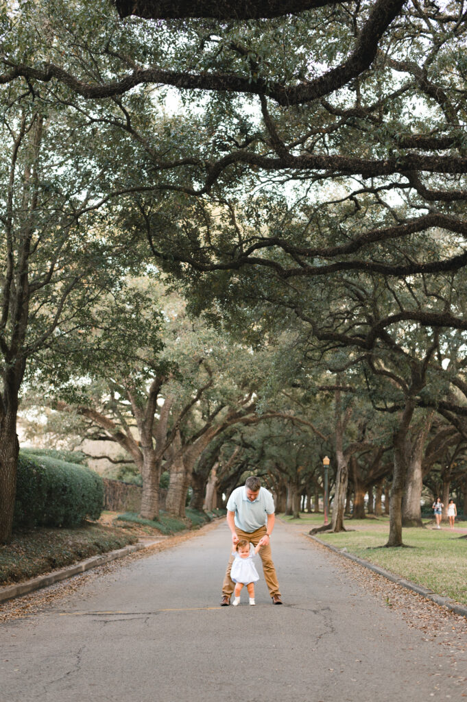A father holds the hands of his infant child learning to walk in an image taken on North Blvd, one of the best photo locations in Houston