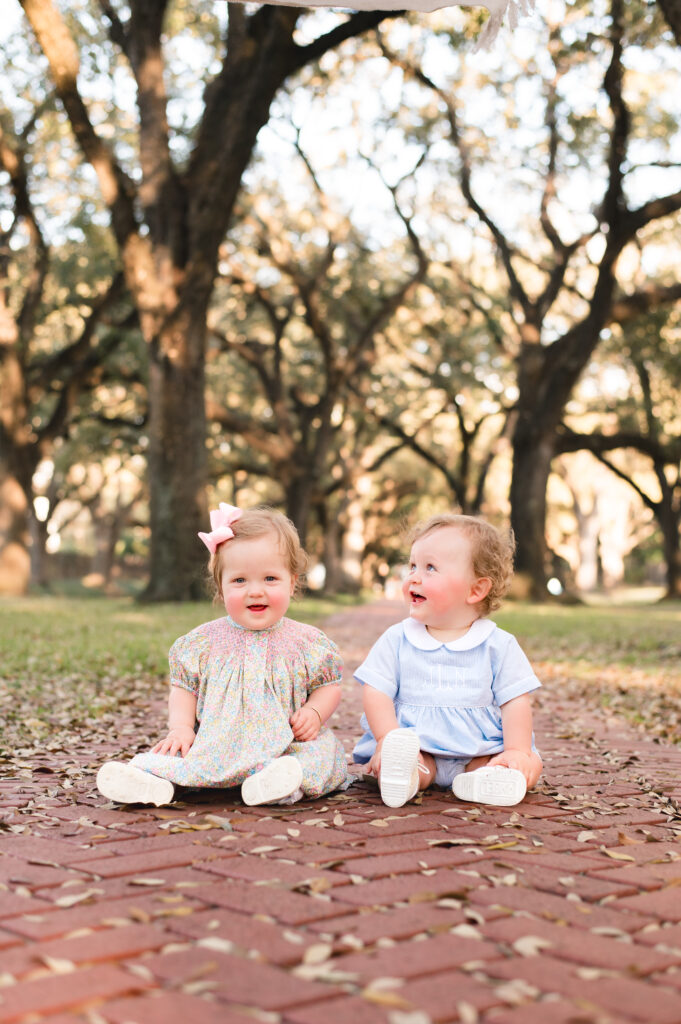 Two infants are seated on a tree lined sidewalk on North Blvd, one of Mel B Photos' favorite places to take photos in Houston