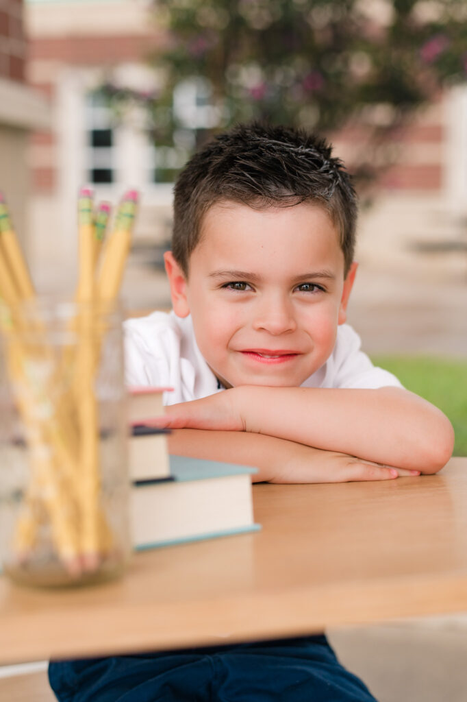 Back to school photography by Houston family photographer, Mel B Photo, showcases a young boy resting his elbows on a school desk 