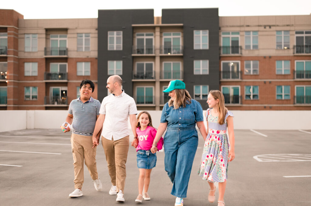 A family of five walks hand-in-hand across a parking lot during a photoshoot with Houston family photographer, Mel B Photo