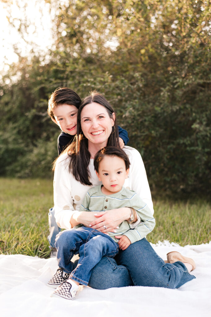 A mother smiles while holding her two young sons during family photography houston tx 