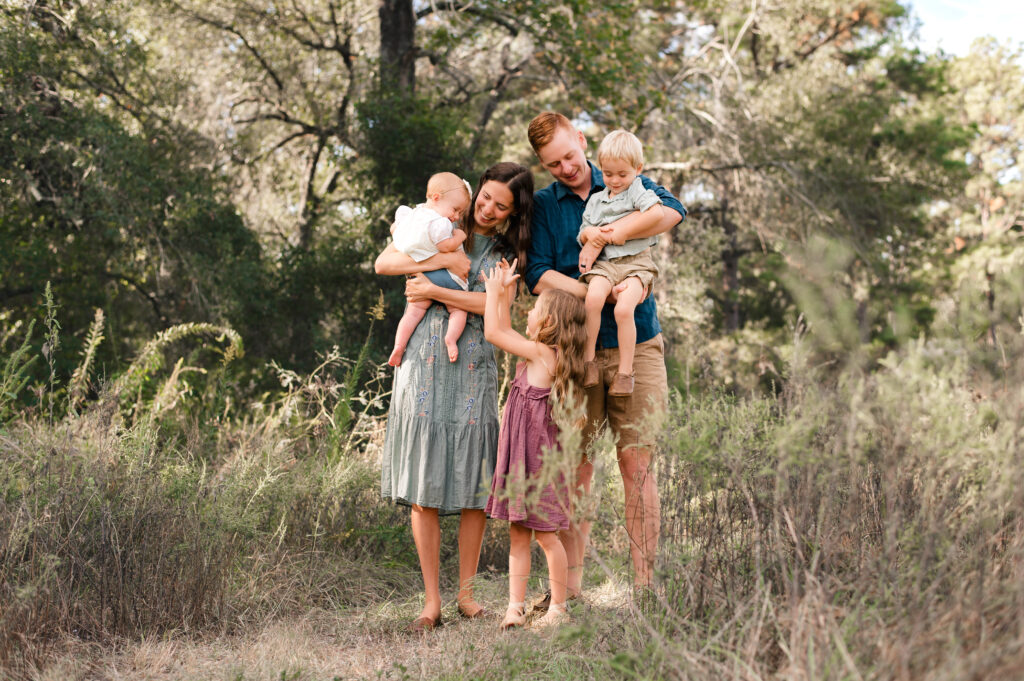 A Texas family of 5 pose in a field in houston in the fall for family photos 