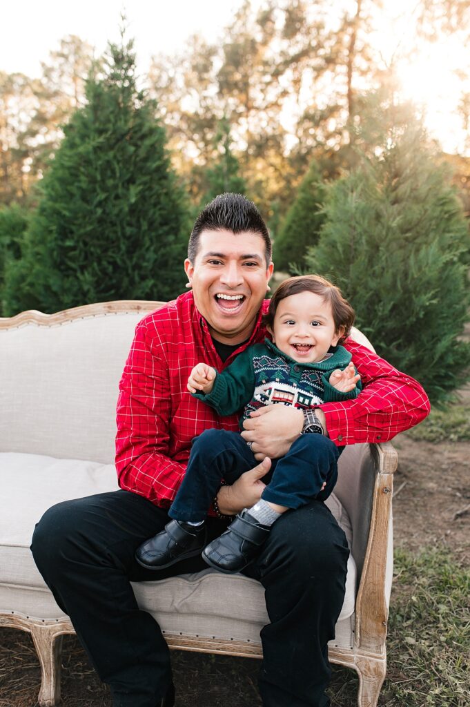 A father smiles with his young son at a Houston tree farm mini session 