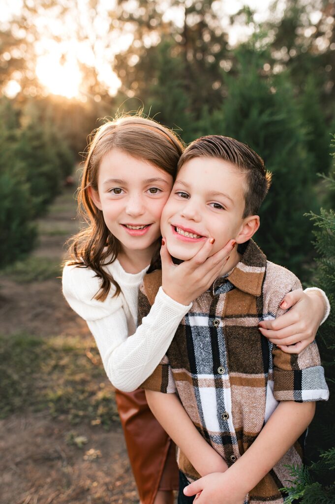 Siblings pose together surrounded by evergreens at a at a Christmas Tree Farm Houston family session