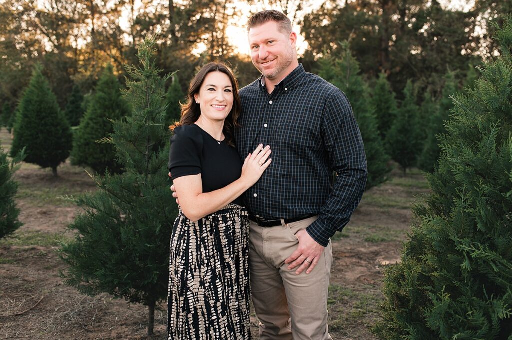 A couple lean in closely for family photos at Spring Creek Growers, a Houston TX Christmas tree farm 