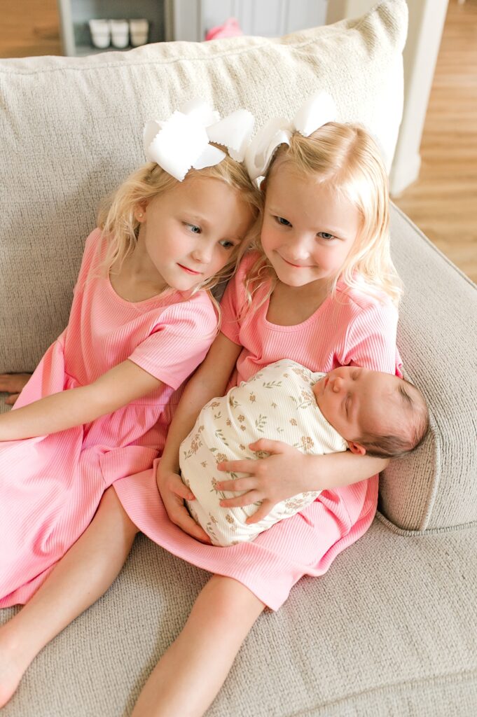 Twin girls hold their newborn baby sister during an in-home session with Houston newborn photographer, Mel B Photo 