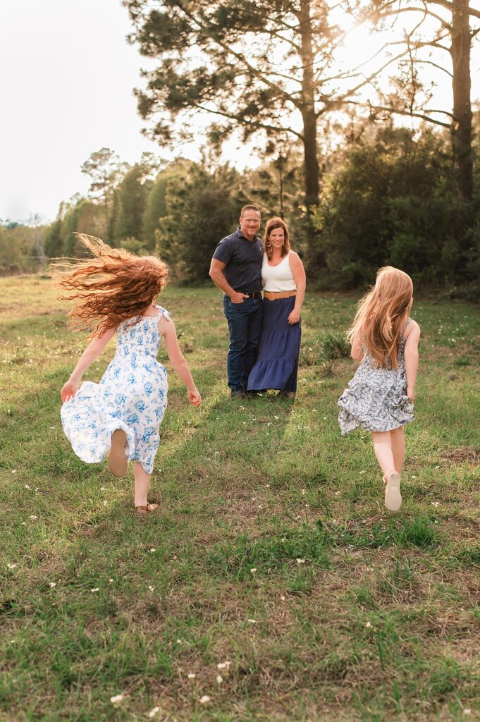 A Cypress photography session captured two young girls running toward their parents during a golden hour family shoot 