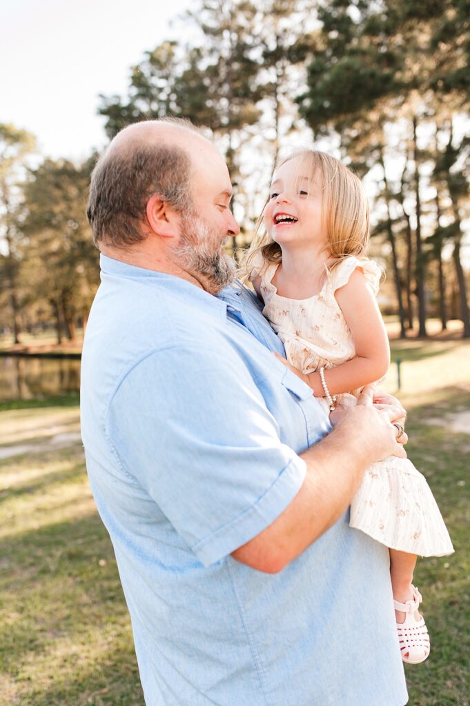 A young girl is snuggled by her grandfather during Cypress family photos 