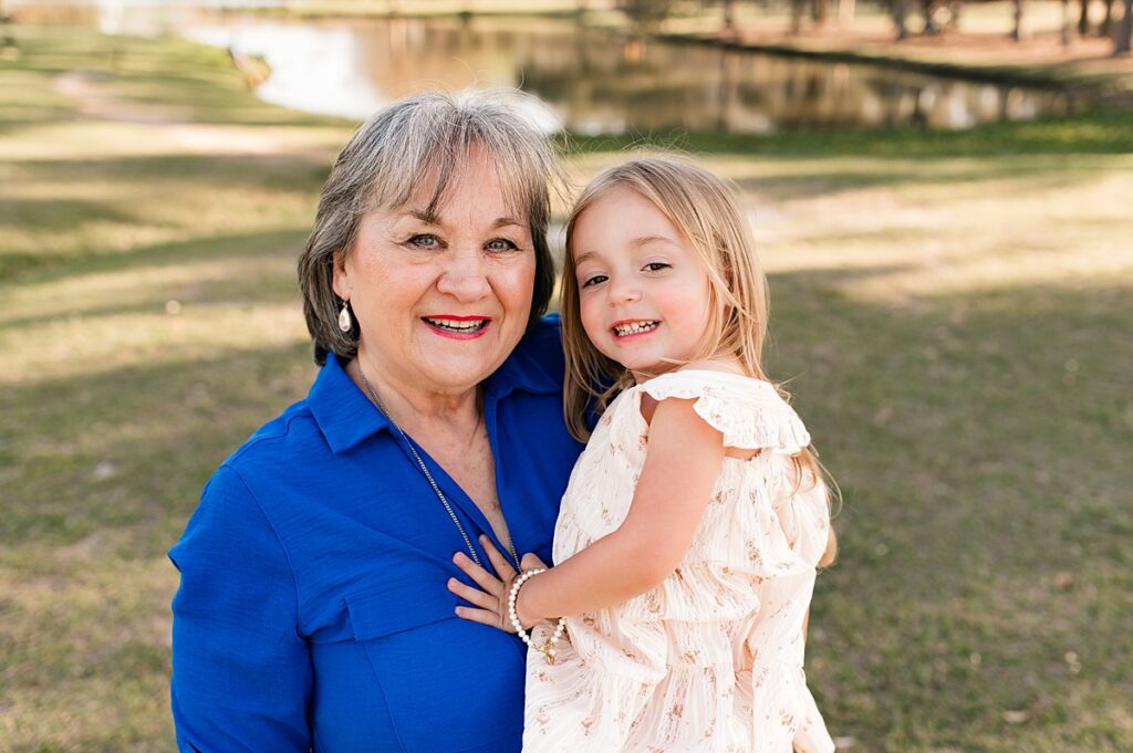 A grandmother in a royal blue shirt holds her young granddaughter in a photo taken during a Cypress photography session with Mel B Photo 