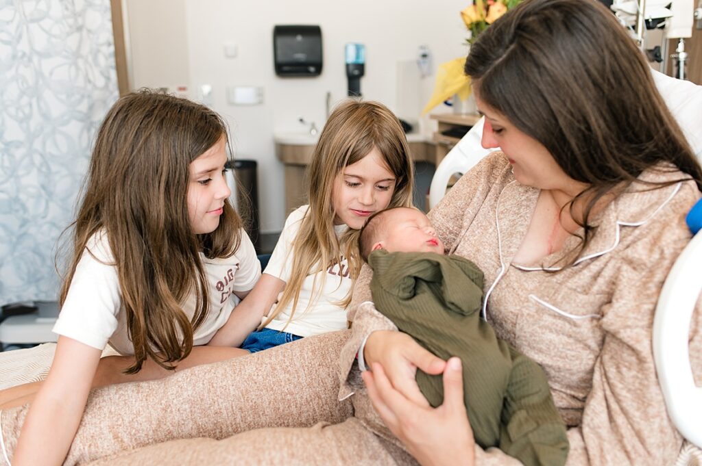 A fresh 48 photoshoot captures two older sisters with their mother in a Houston hospital as she holds their newborn brother 