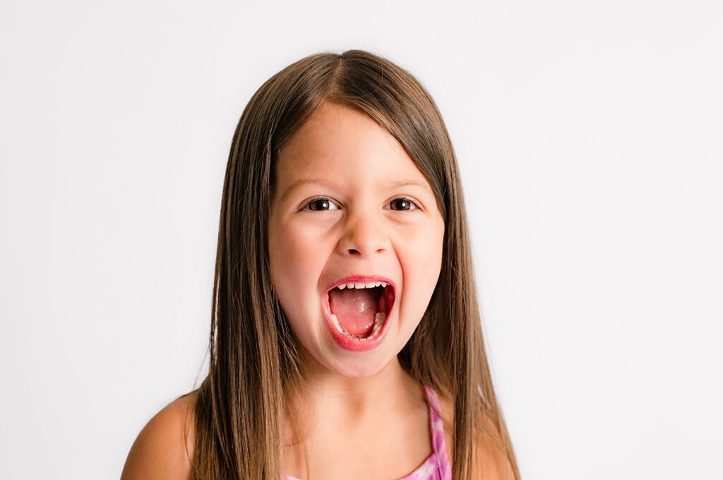 a Houston school portrait showcases a young girl smiling big for the camera in a personality-filled pose