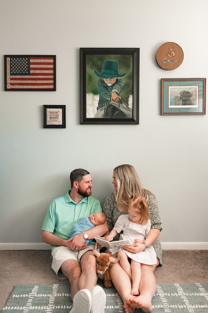 A mother and father are seated with their toddler and newborn in the floor during Houston newborn nursery photos