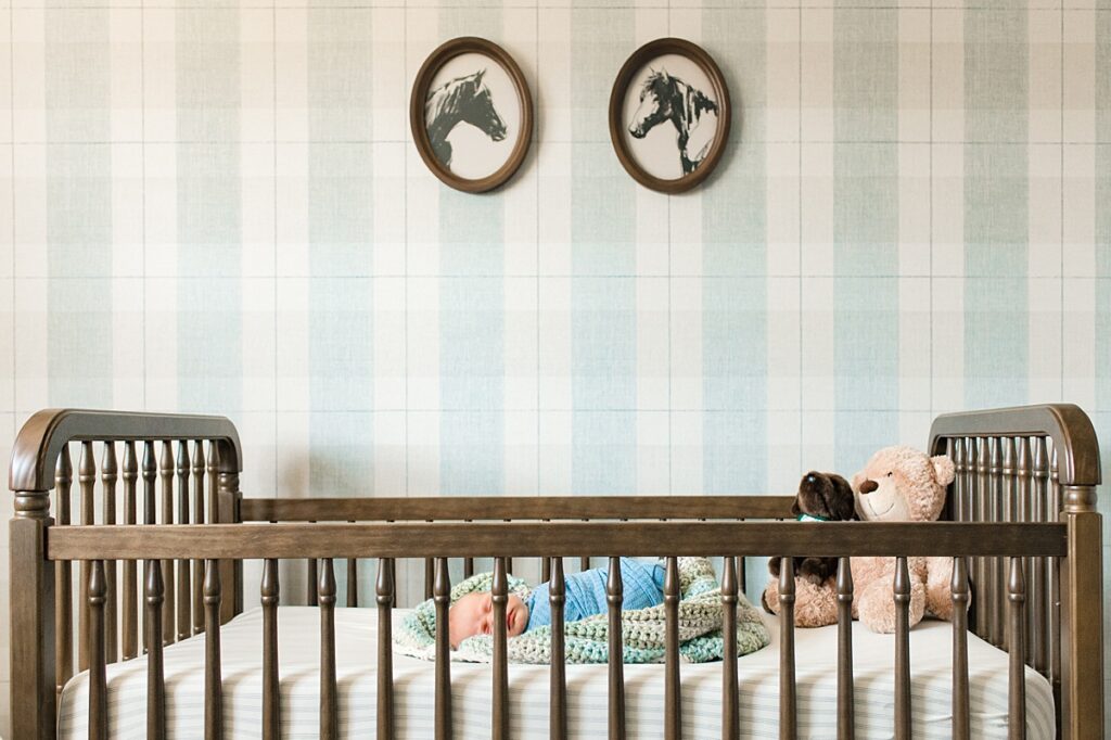 A baby boy in a blue swaddle is placed in his wooden crib during newborn nursery photos with Houston newborn photographer, Mel B Photo