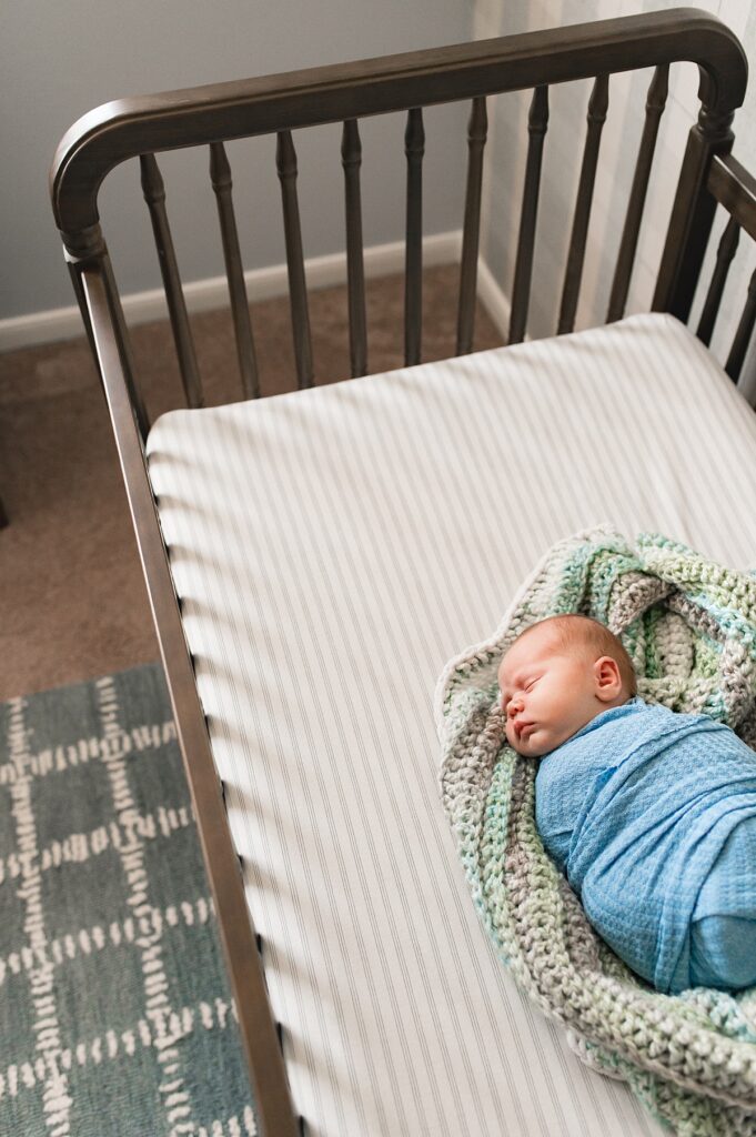 A sleeping newborn sleeps in his crib during a Houston In Home Lifestyle Newborn Photography
