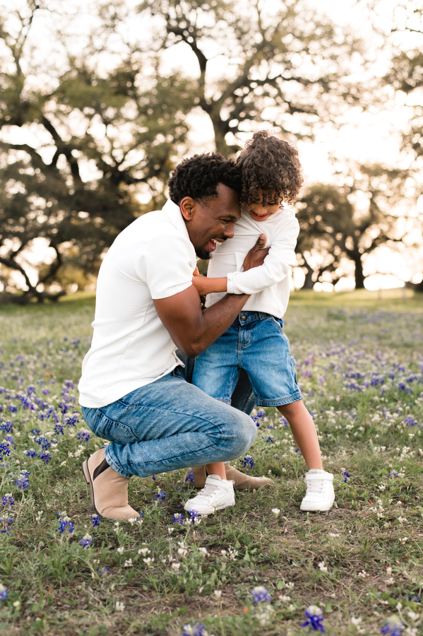 A father tickles his son in a photo taken during bluebonnets in brenham tx