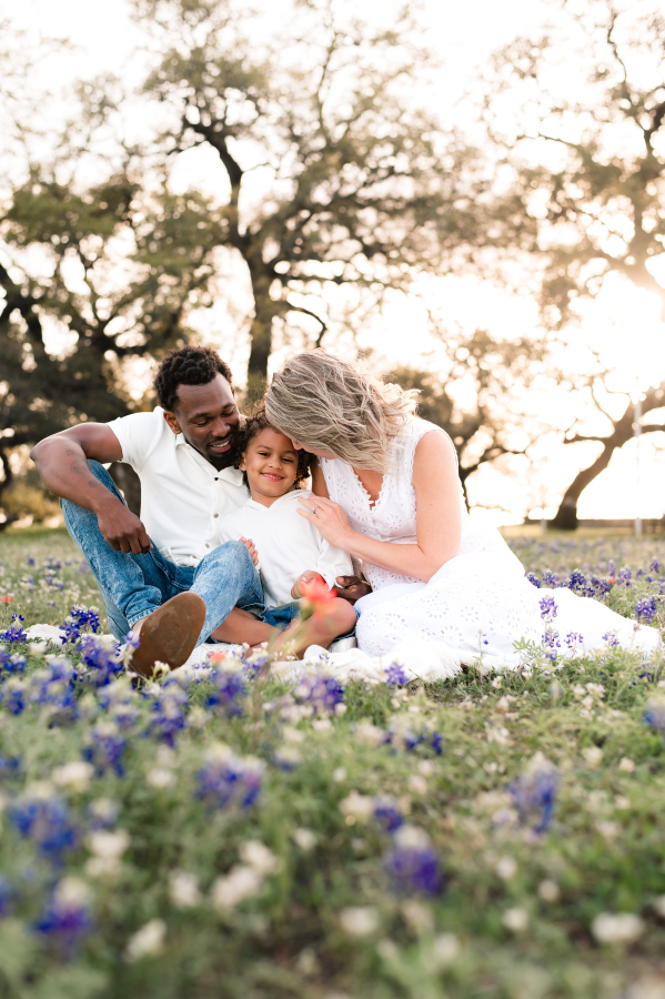 A mother and father snuggle their young son in a field of bluebonnets in brenham tx