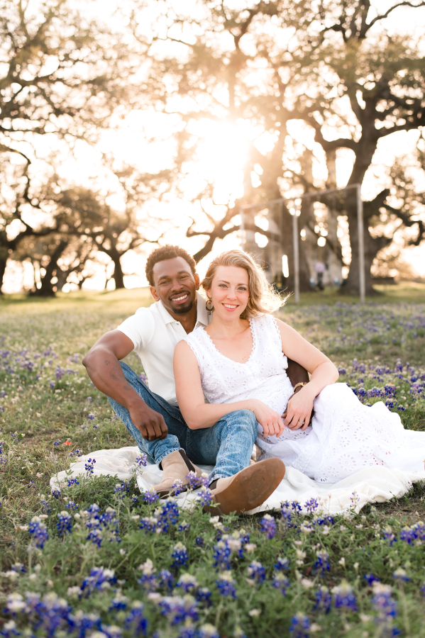 A young couple wearing white pose for bluebonnet photos texas