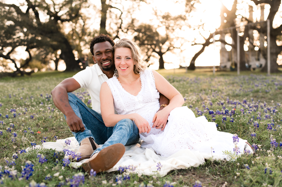 A young couple lean into each other for bluebonnet photos in brenham tx