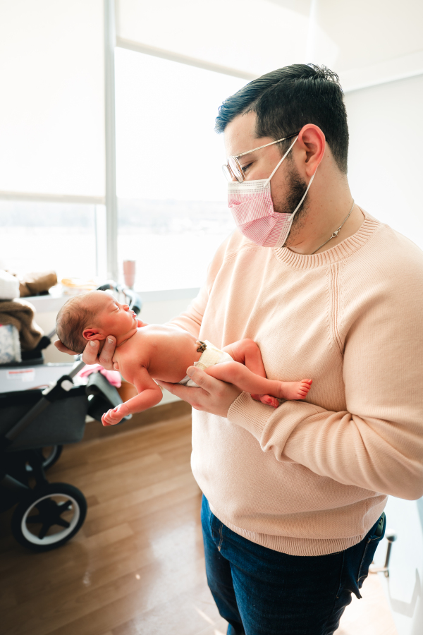 A father holds his newborn daughter during a first 48 newborn photography session at Houston Methodist 