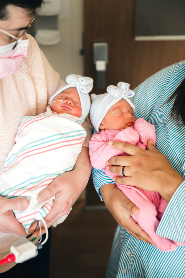New parents hold their newborn twin girls during a fresh 48 photoshoot in a nicu Houston TX