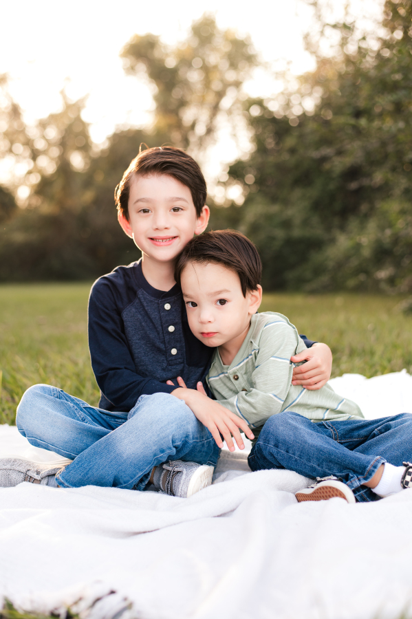 A young boy leans into his older brother in a photo taken by Cypress family Photographer in the Bridgeland community 