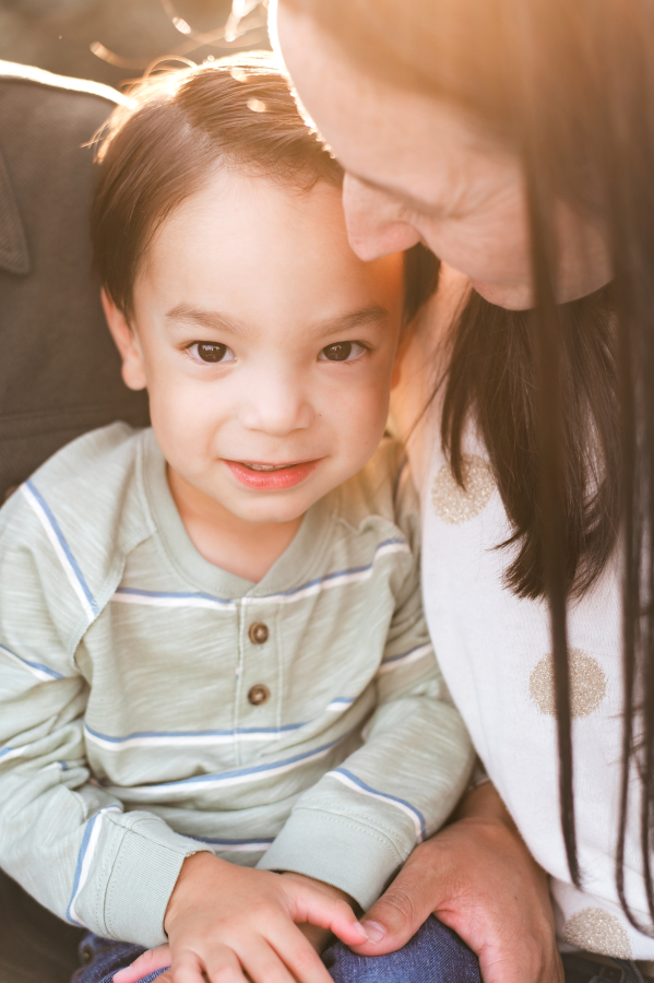 A close up photo taken by a Cypress family photographer showcases a young boy being held by his parents in a Bridgeland community park