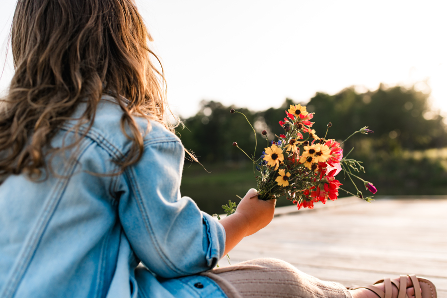 A young girl holds a bouquet of wildflowers in a photo taken for a guide of kid friendly houston tx activities. 