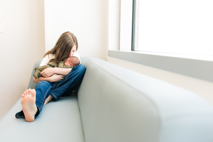 An older sibling snuggles her newborn baby brother in a green swaddle during a Fresh 48 photoshoot at a Houston TX hospital