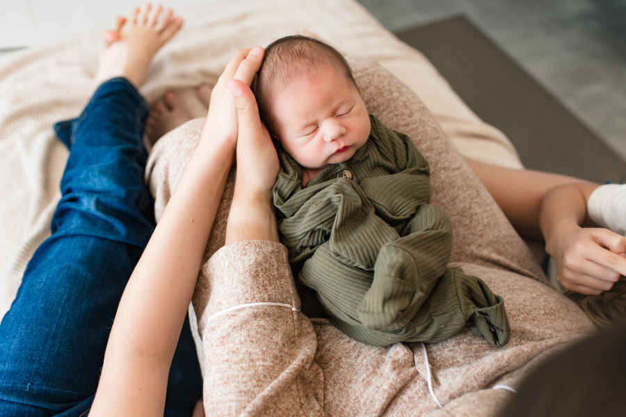 A newborn baby sleeps on his mother's lap during a Houston newborn fresh 48 session