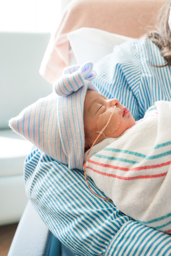 A newborn baby girl sleeps in her mother's arms during a Houston TX fresh 48 photoshoot