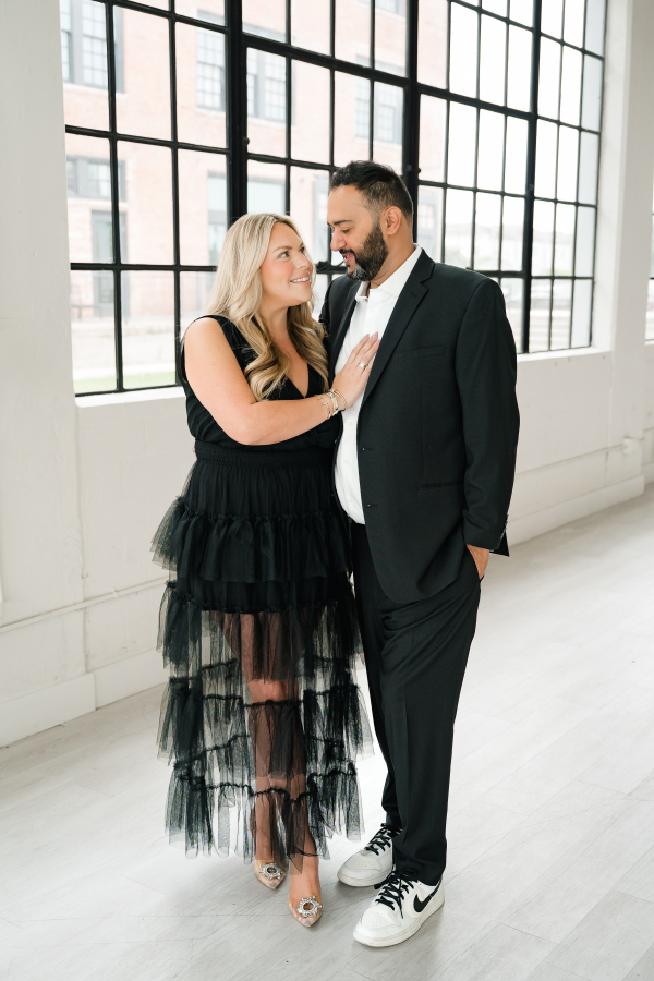 A Texas couple poses before a wall of windows during a Houston studio photography session.