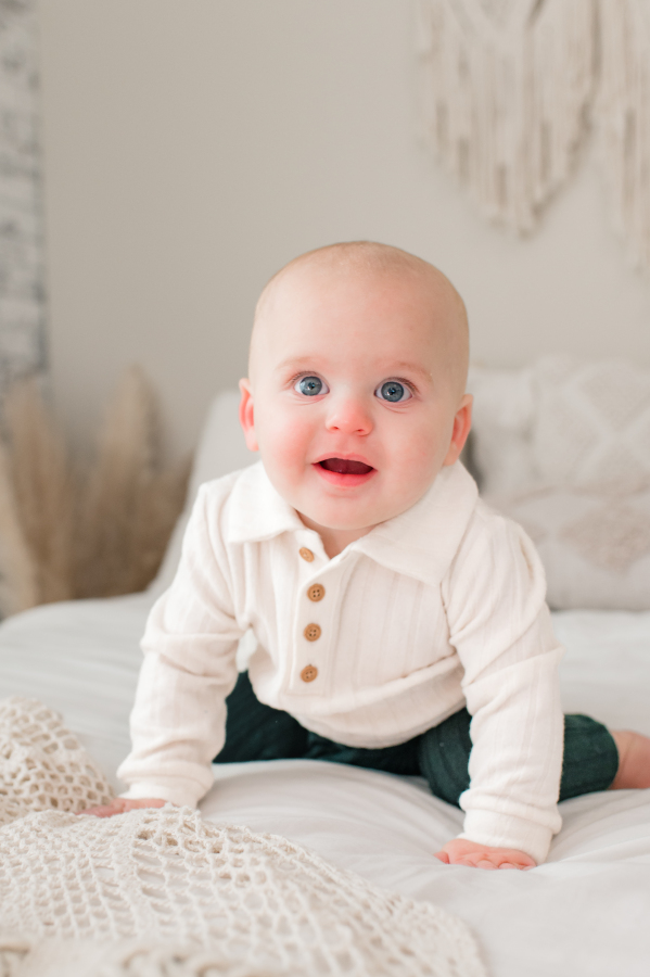 An infant crawls atop a cream blanket during a photoshoot in a photography studio in Houston TX.